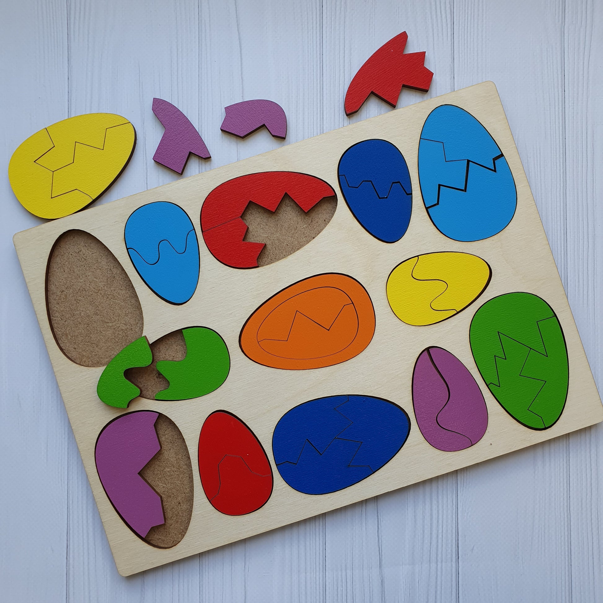 Wooden eggs taken apart into two and three pieces beside the tray, showing how each egg splits