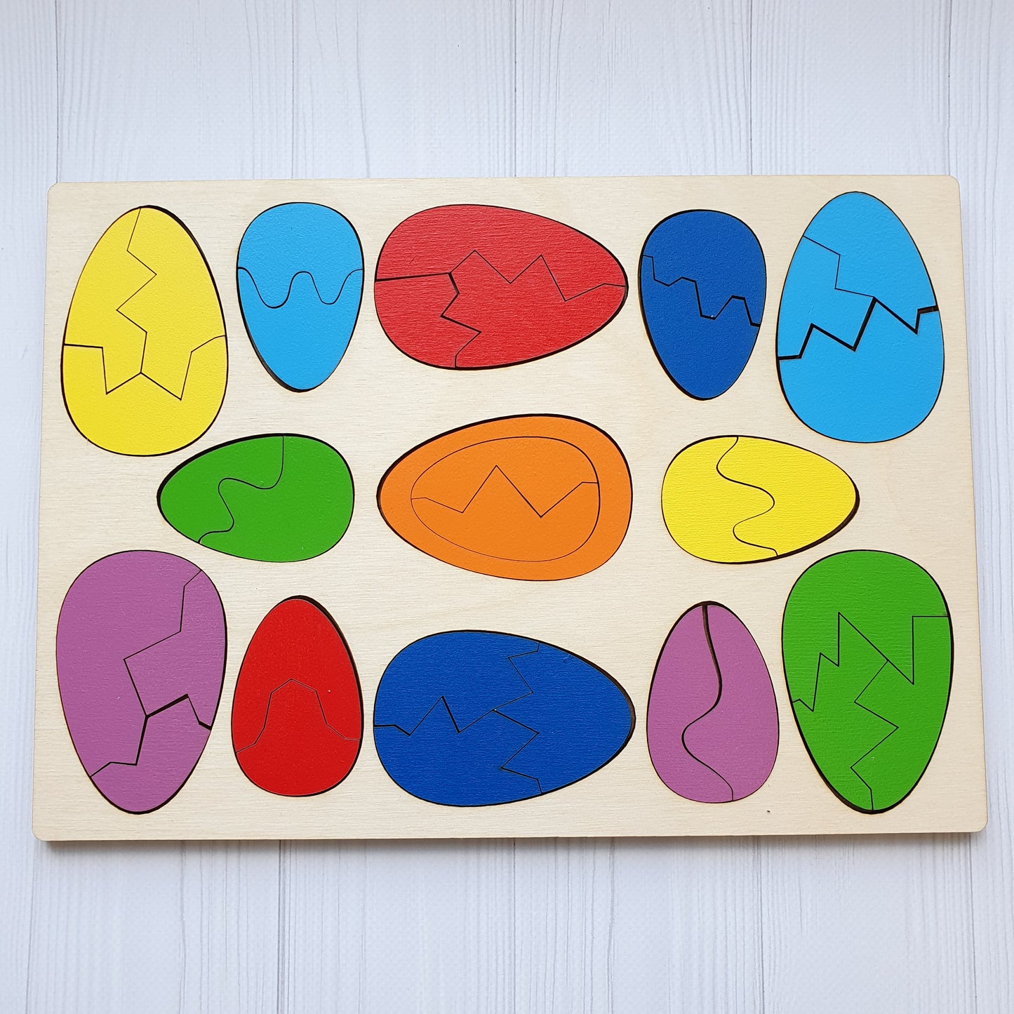 All thirteen wooden eggs assembled whole, showing both sizes and the full range of colours