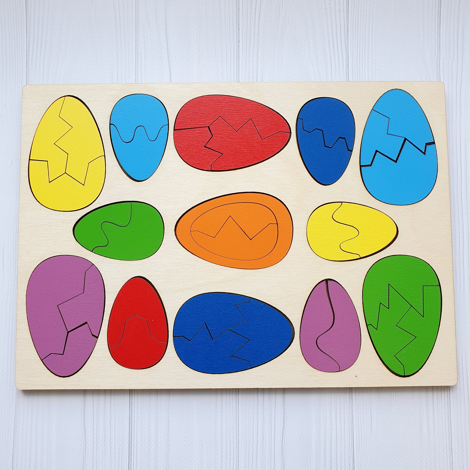 All thirteen wooden eggs assembled whole, showing both sizes and the full range of colours