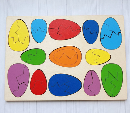 Thirteen coloured wooden eggs sitting in their egg-shaped sockets in the plywood tray